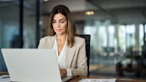 Business professional reviewing information on a laptop in a modern office, symbolizing financial compliance and risk oversight.